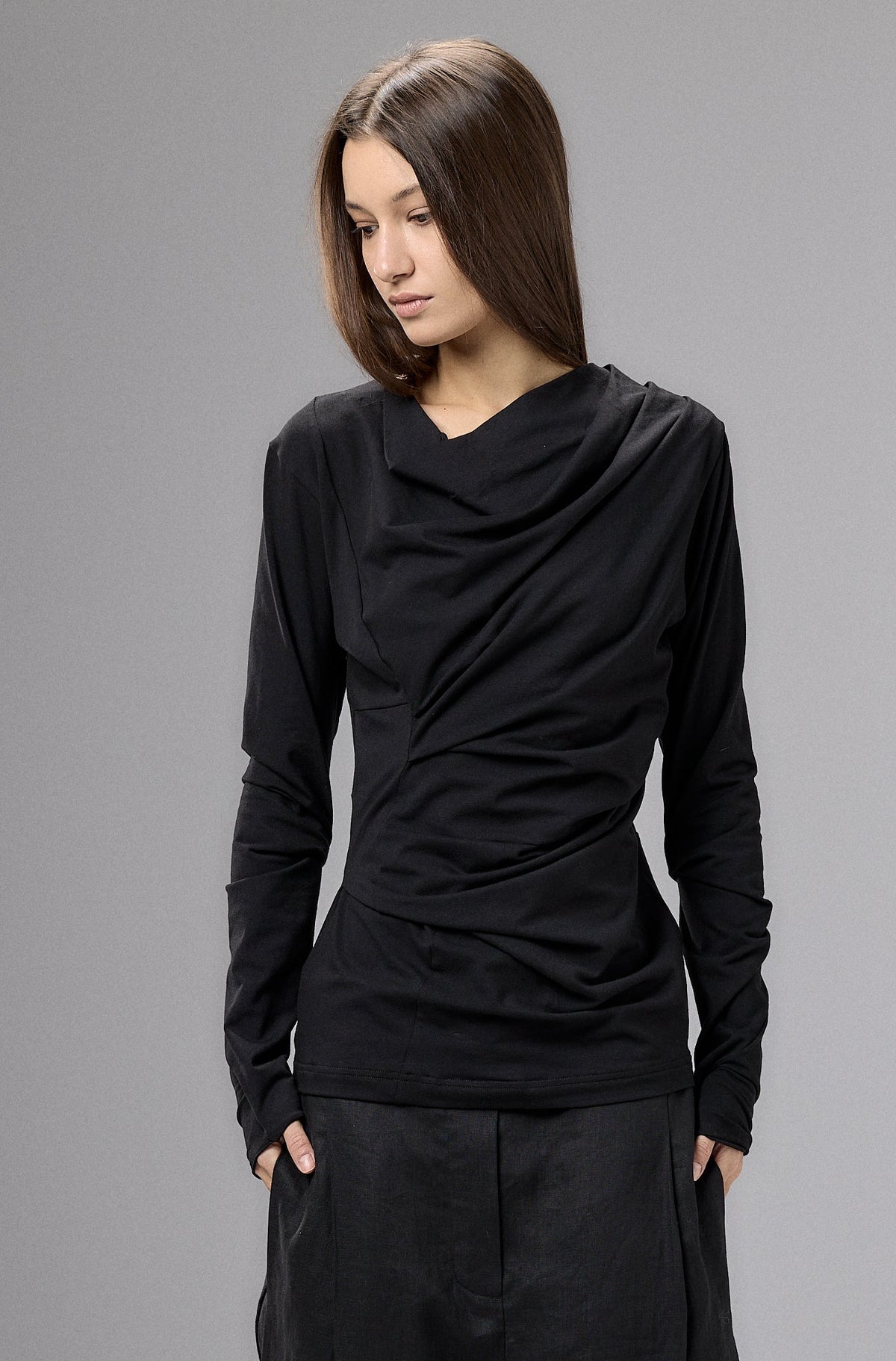 Person wearing a black outfit against a gray background