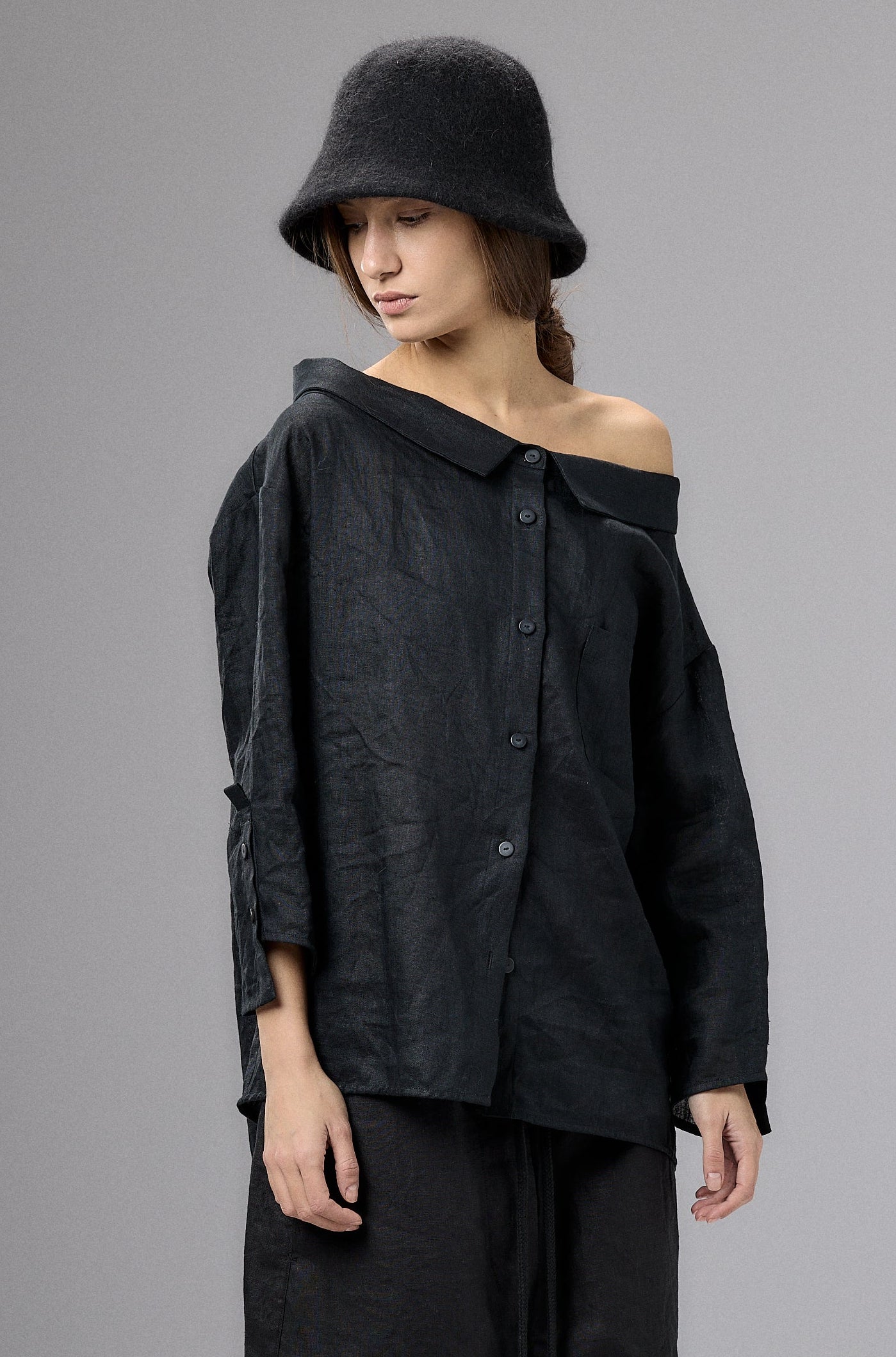 Person wearing a black outfit with a hat on a gray background