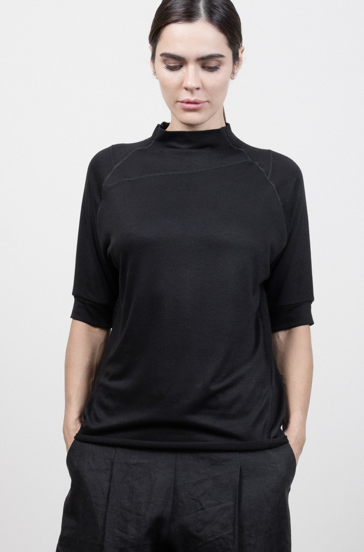 Person wearing a black outfit with wide-leg pants against a white background