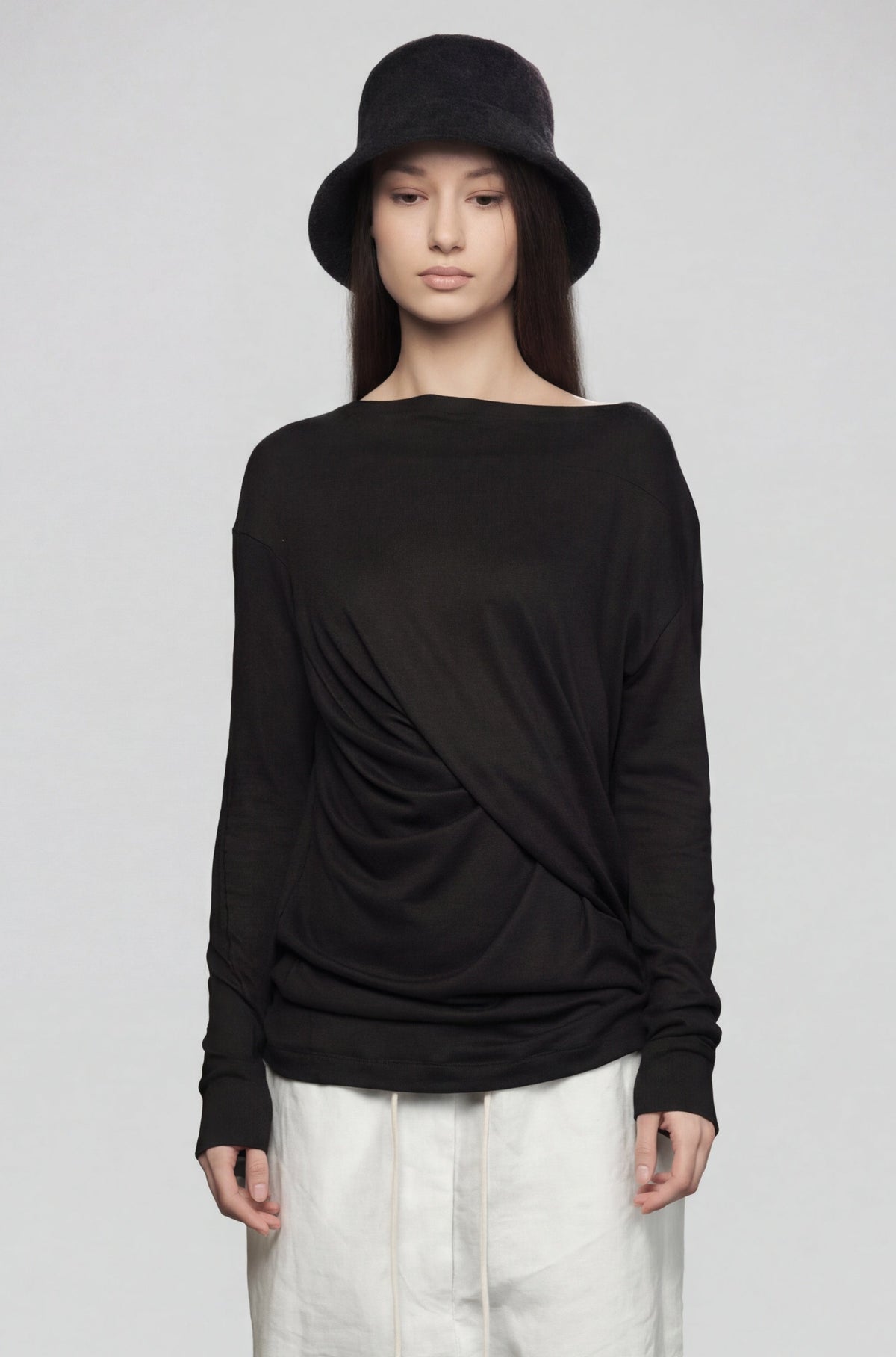 Person wearing a black long-sleeve top and white pants on a gray background