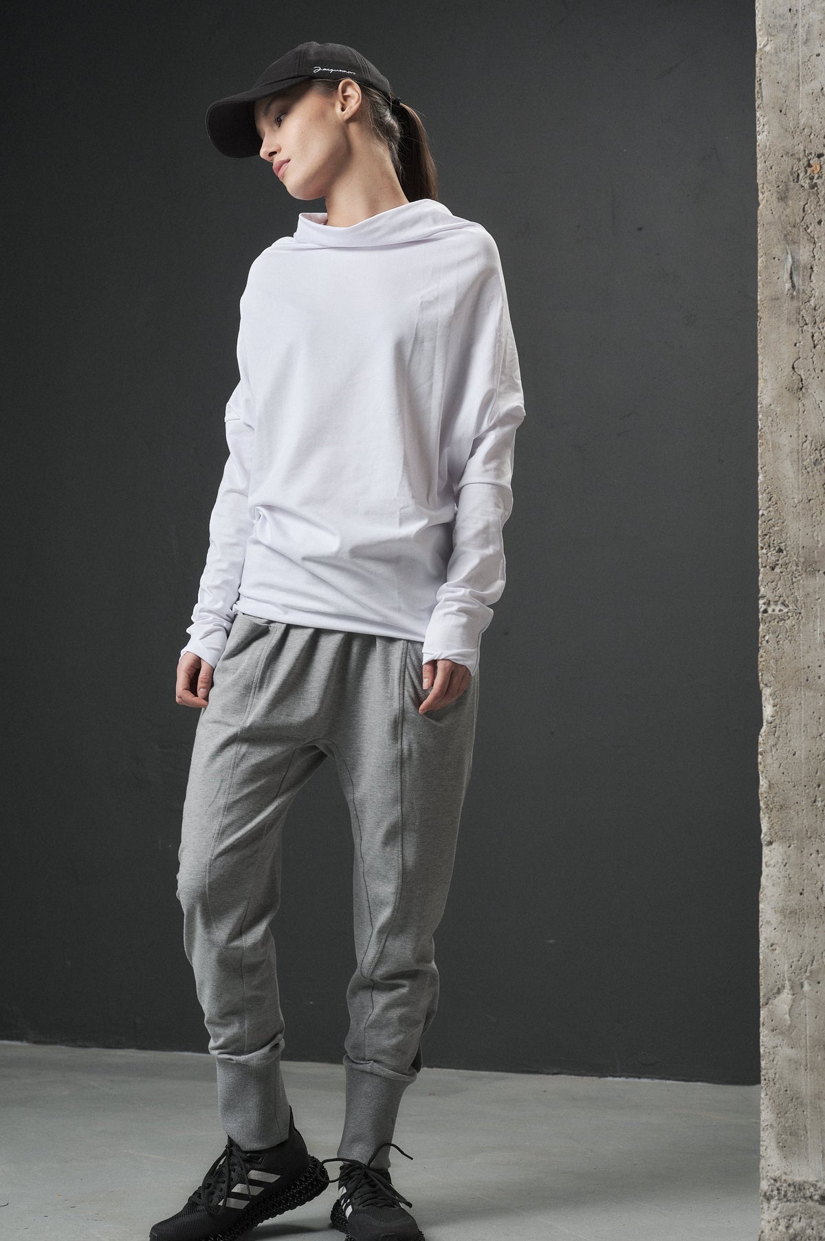 Person wearing a light gray outfit with a cap in an industrial setting