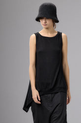 Person wearing a black sleeveless top and pants with a hat against a gray background