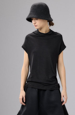 Person wearing a black outfit with a wide-brimmed hat against a gray background