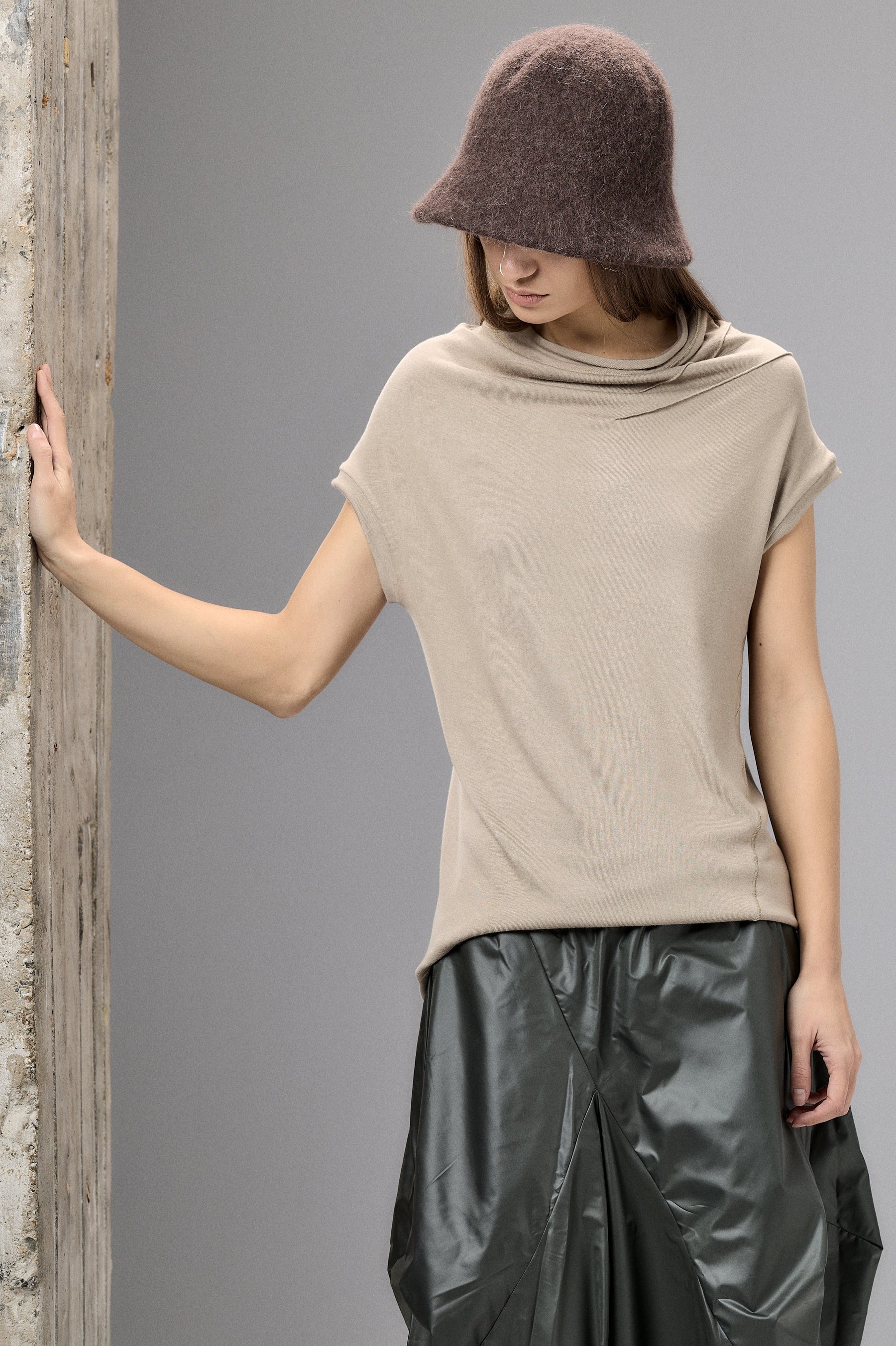 Woman wearing a beige top and black leather skirt against a gray background