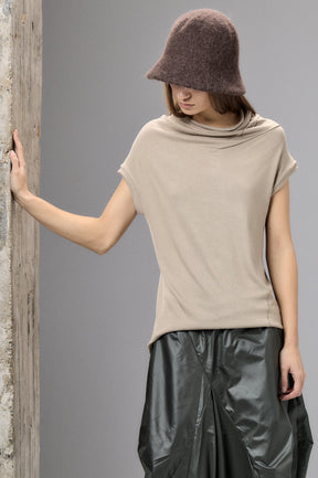 Woman wearing a beige top and black leather skirt against a gray background