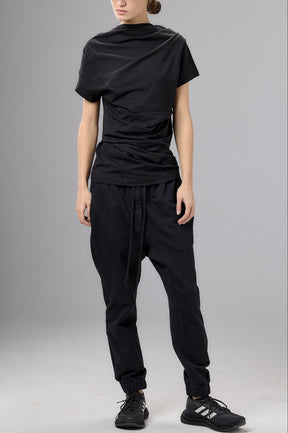Person wearing a black outfit with a cap against a gray background