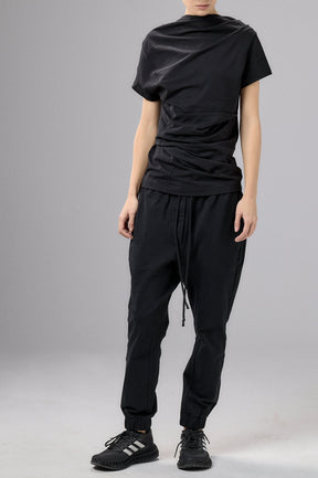 Person wearing a black outfit with a cap on a gray background