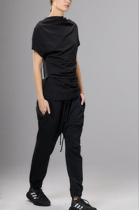 Person wearing a black outfit with a cap against a gray background