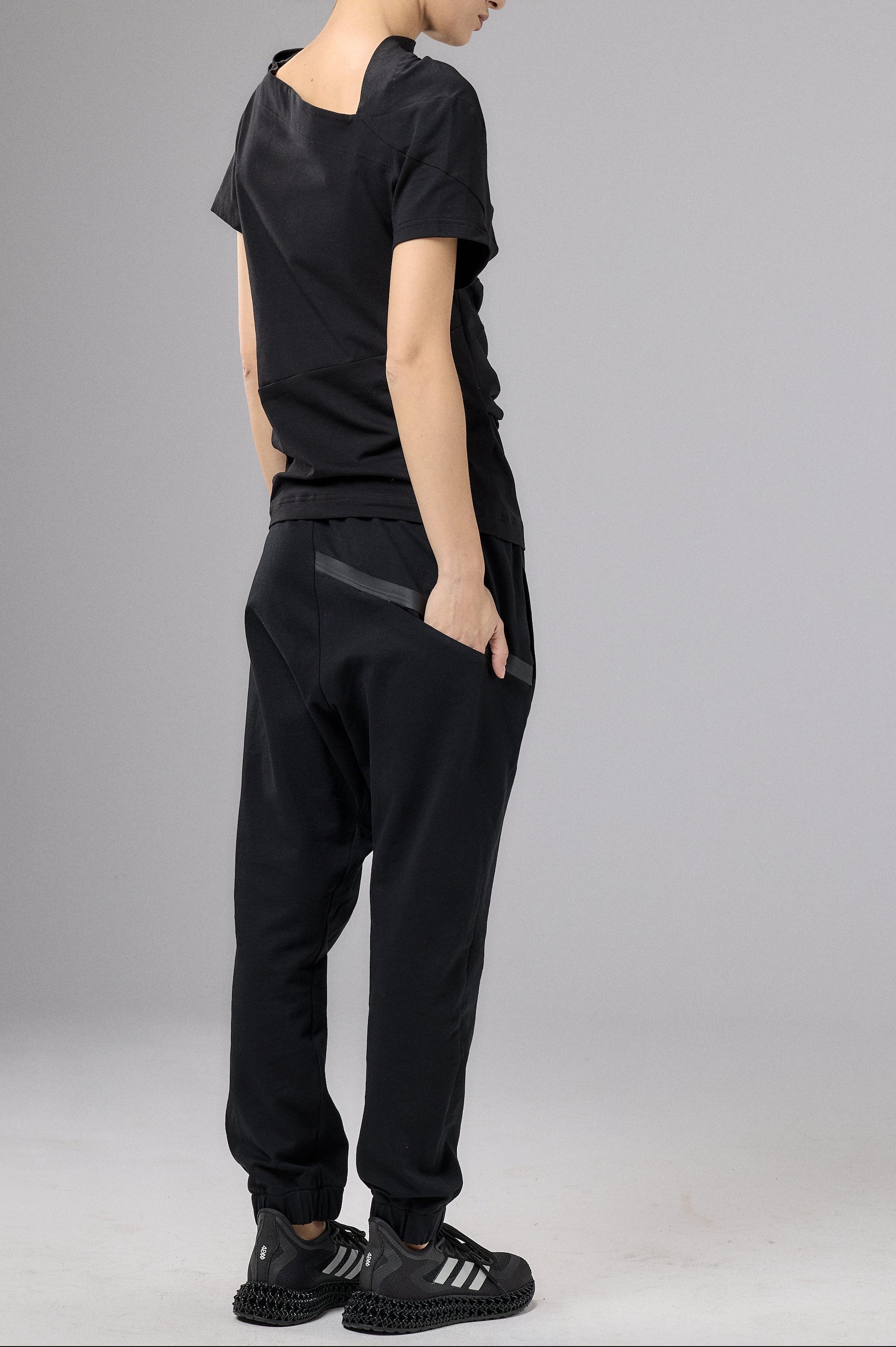 Person wearing a black outfit with a cap on a gray background
