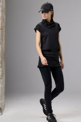 Person wearing a black outfit with a cap on a gray background