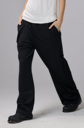 Person wearing a white t-shirt, black pants, and a black cap on a gray background