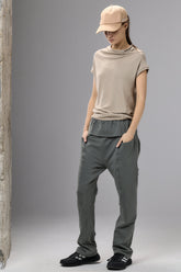 Person wearing a beige cap, t-shirt, and gray pants against a plain background