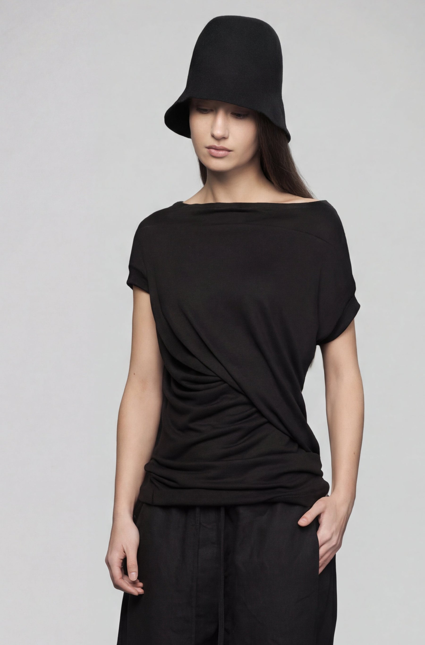 Person wearing a black outfit with a hat on a gray background