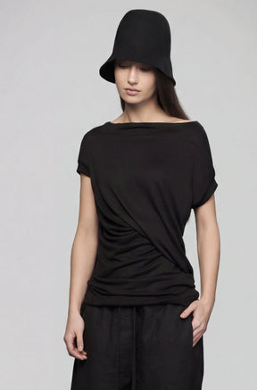 Person wearing a black outfit with a hat on a gray background