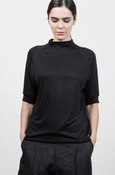 Person wearing a black outfit with wide-leg pants against a white background