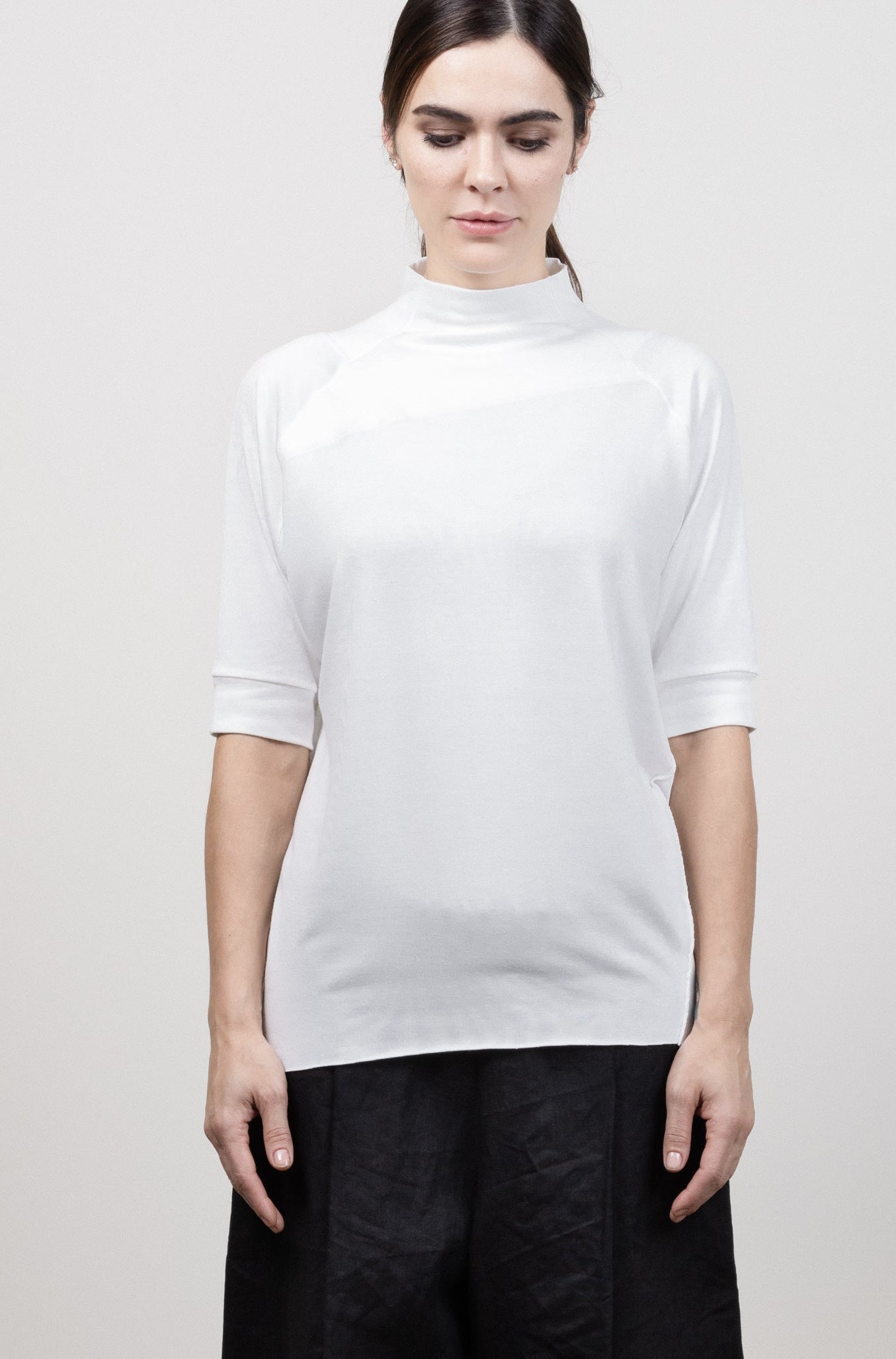 Person wearing a white top and black pants on a plain background