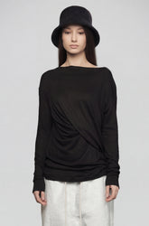 Person wearing a black long-sleeve top and white pants on a gray background
