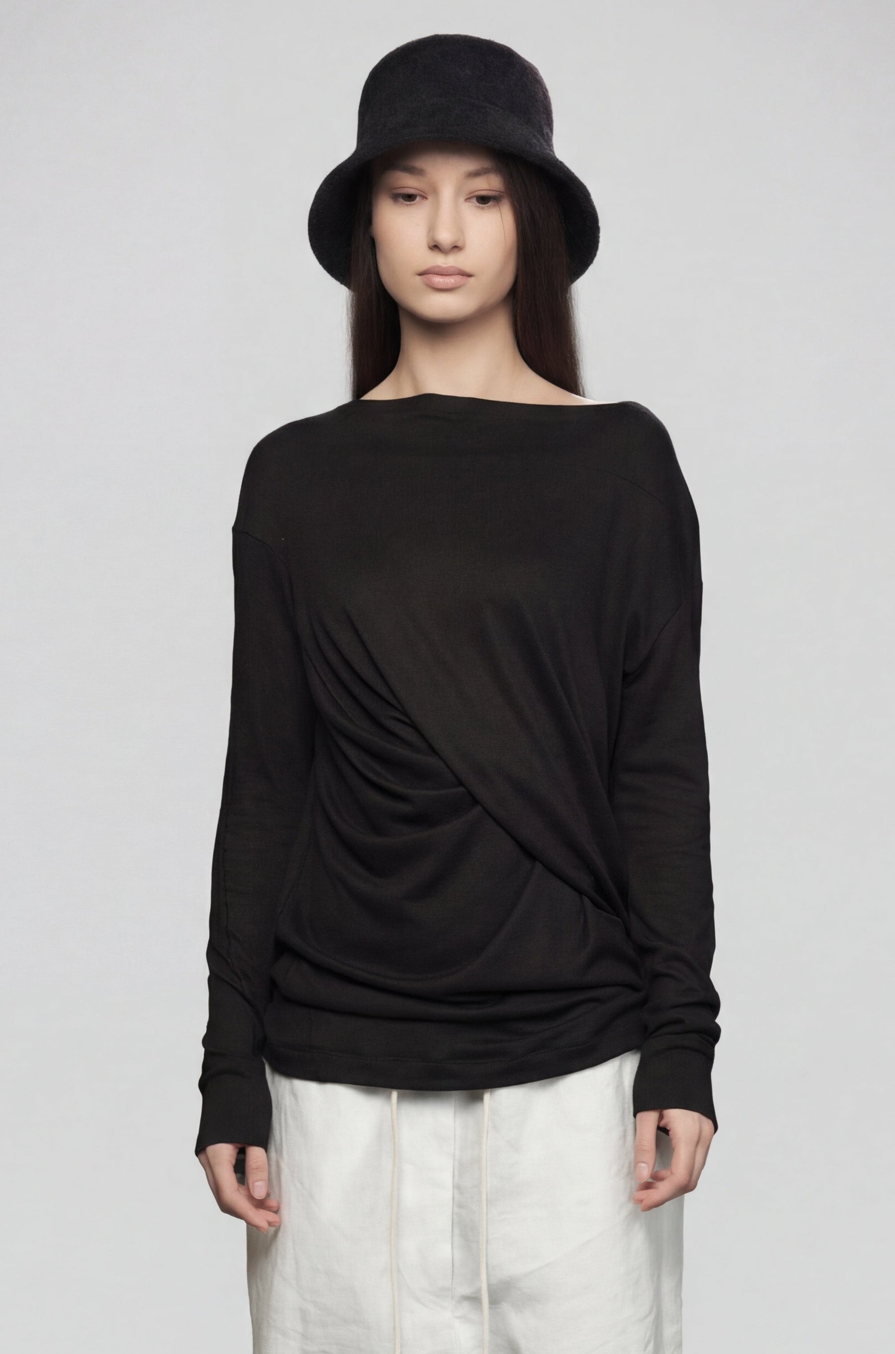Person wearing a black long-sleeve top and white pants on a gray background