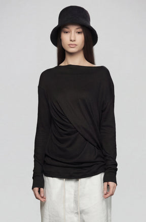 Person wearing a black long-sleeve top and white pants on a gray background