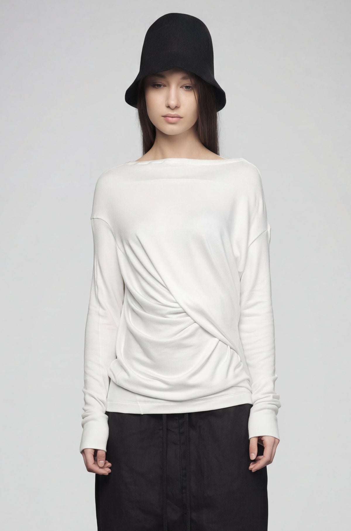 Person wearing a white sweater and black pants on a plain background