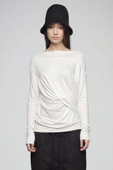 Person wearing a white sweater and black pants on a plain background