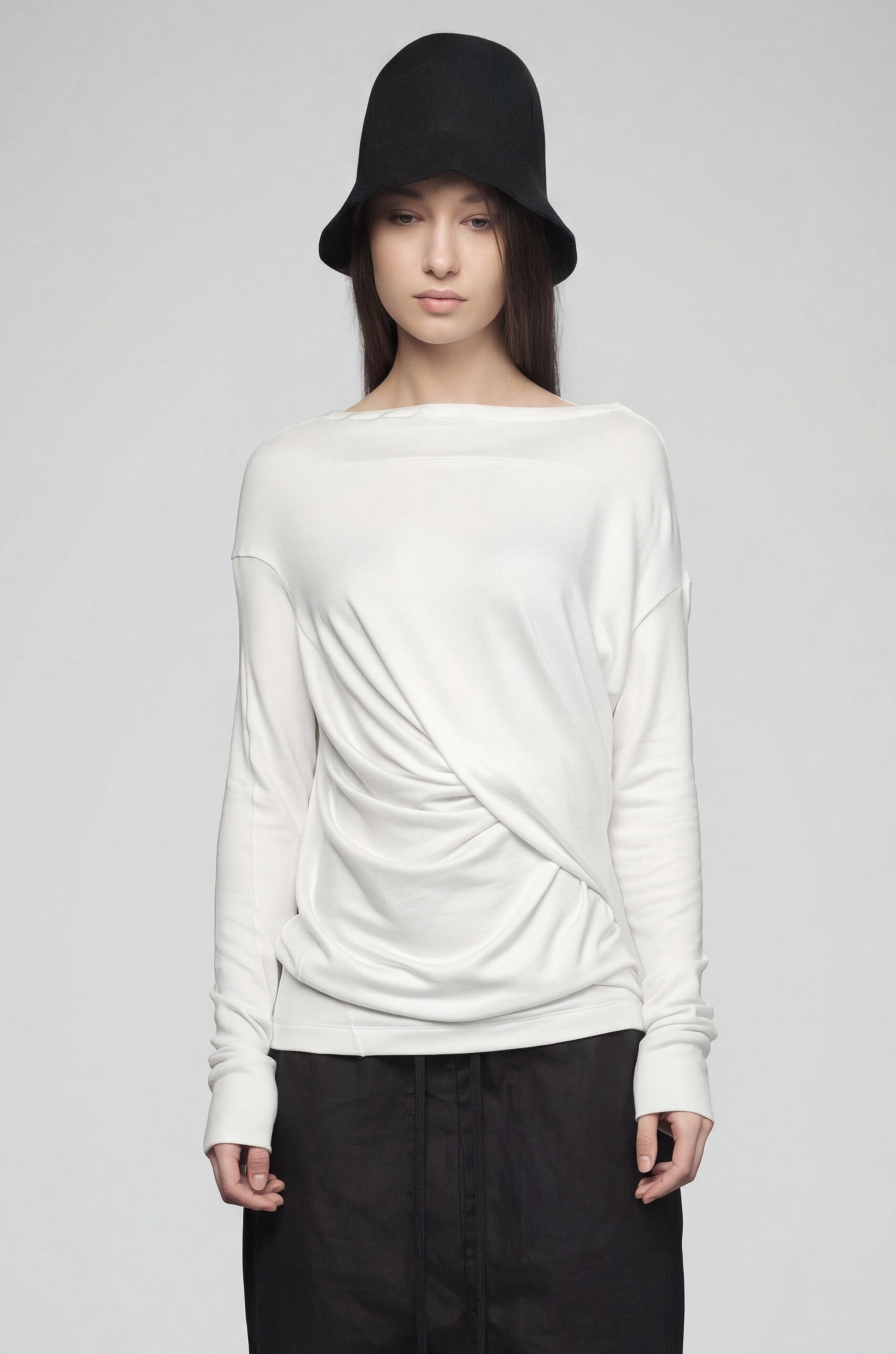 Person wearing a white sweater and black pants on a plain background